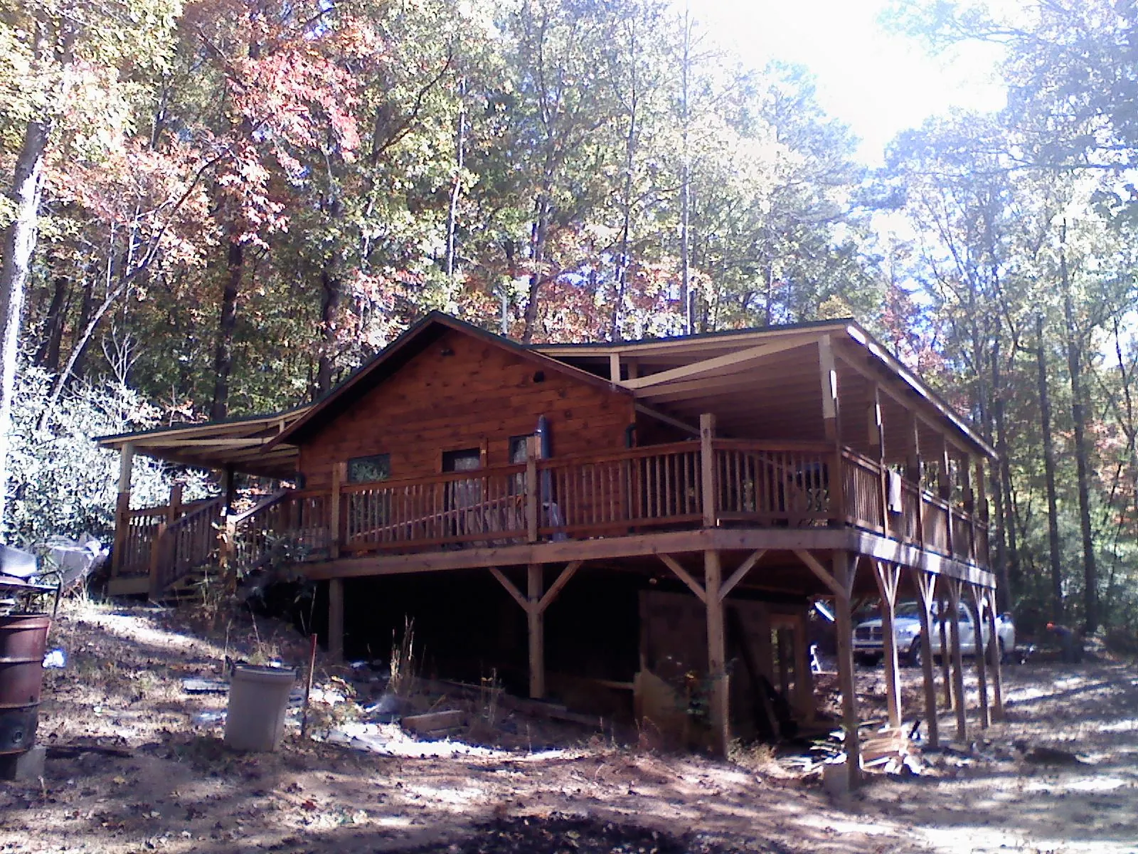 Log cabin with a wraparound porch and metal roof in the fall in Lake Forest